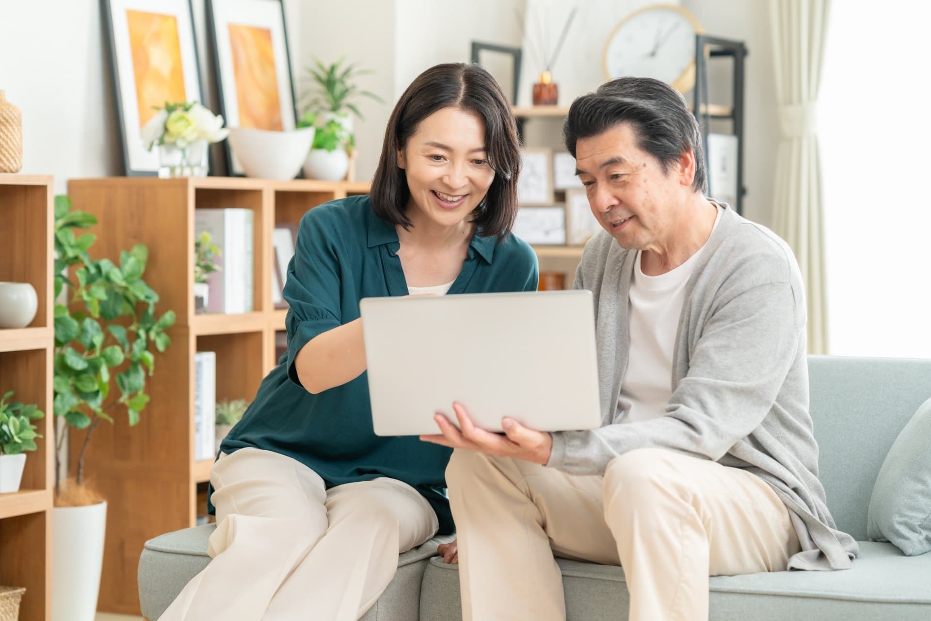 リビングのソファで、ノートパソコンを一緒に見ているご夫婦