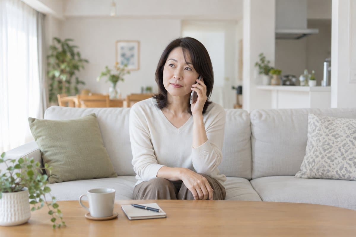 リビングのソファで、電話の相手の話を聞いている女性
